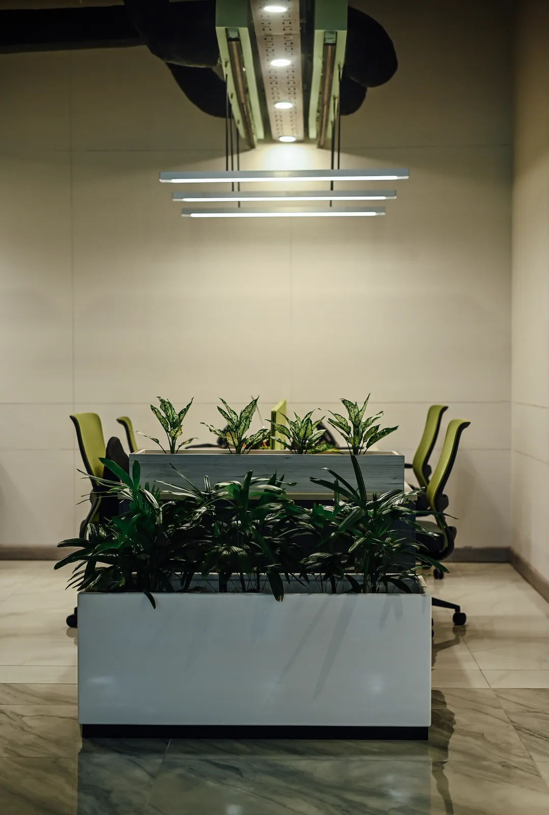 PSO House, 8th-floor rehabilitation, Karachi: A shared table beyond a low planted divider. 8th-floor rehabilitation photography.