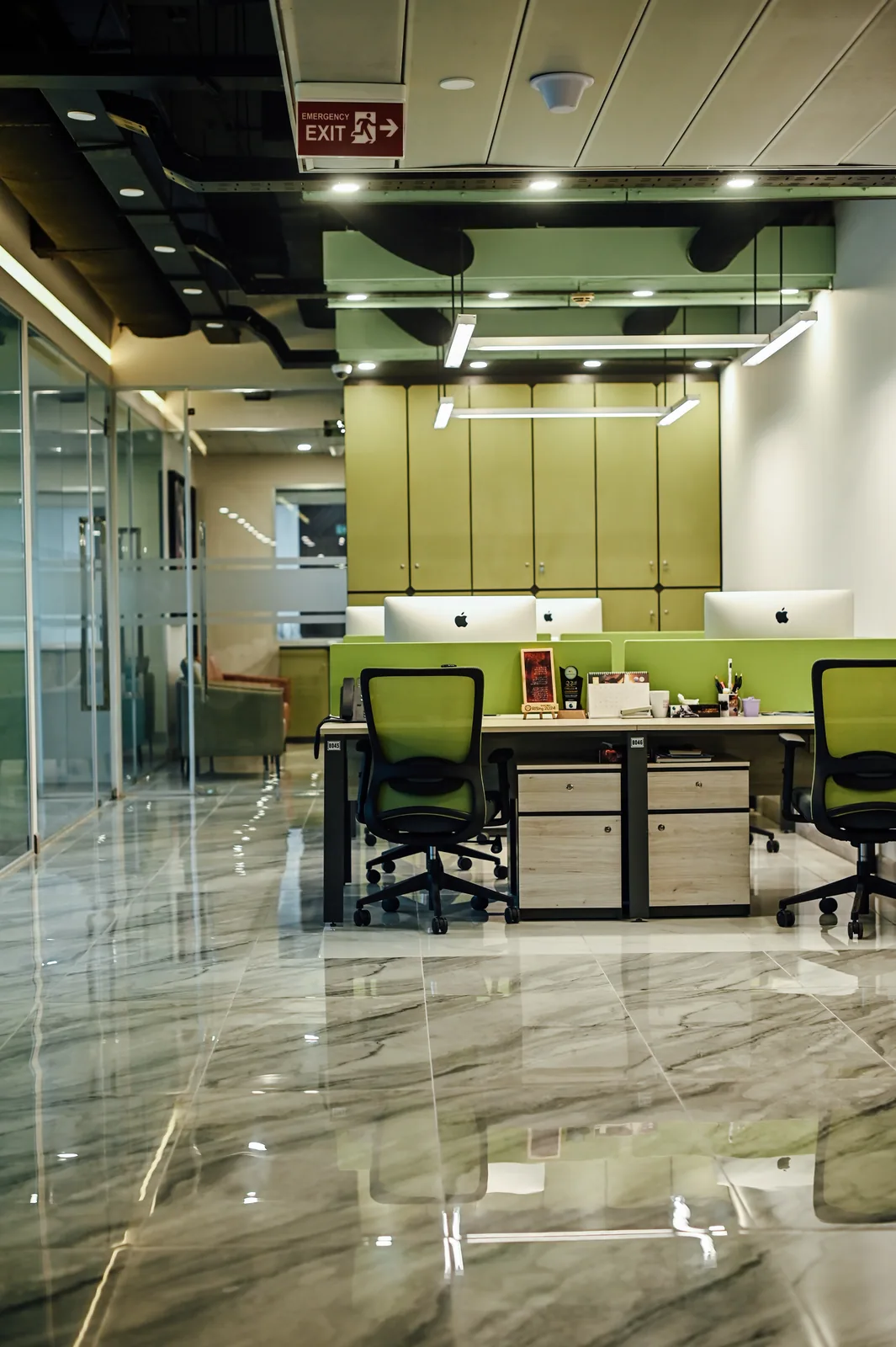 PSO House, 8th-floor rehabilitation, Karachi: Green chairs and storage beneath linear lights. 8th-floor rehabilitation photography.