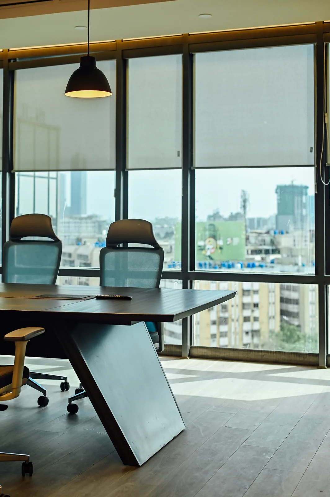 PSO House, 8th-floor rehabilitation, Karachi: A timber meeting table beside city glazing. 8th-floor rehabilitation photography.