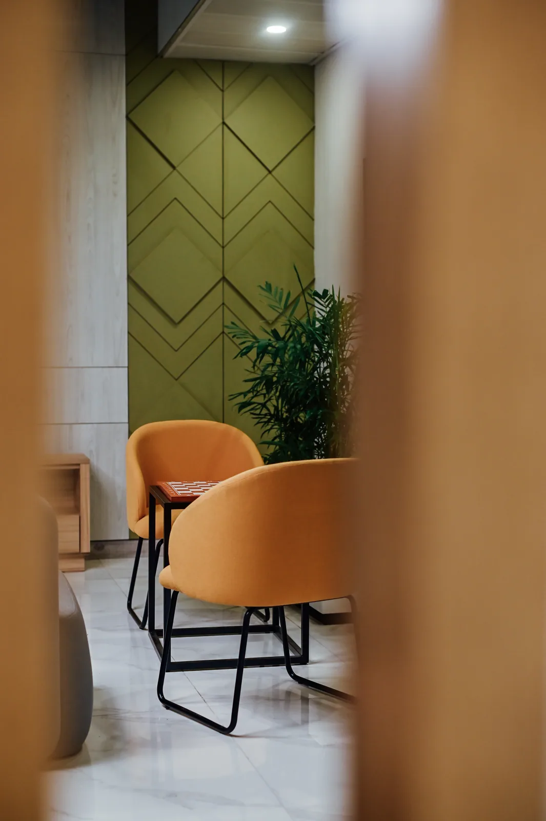 PSO House, 8th-floor rehabilitation, Karachi: Orange chairs seen through a timber screen. 8th-floor rehabilitation photography.