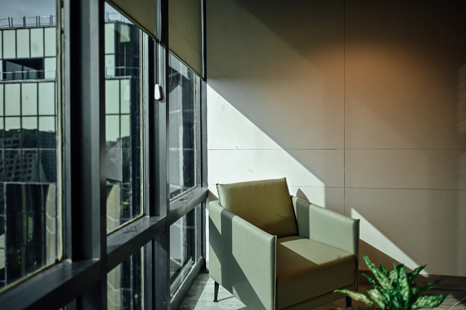 PSO House, 8th-floor rehabilitation, Karachi: Sunlight falls across a lounge chair and wall. 8th-floor rehabilitation photography.