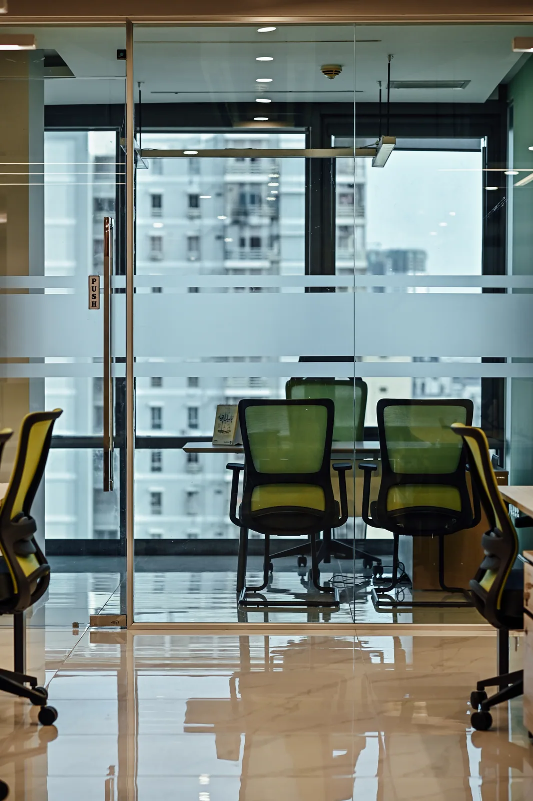 PSO House, 8th-floor rehabilitation, Karachi: A glazed meeting room beyond the shared desks. 8th-floor rehabilitation photography.