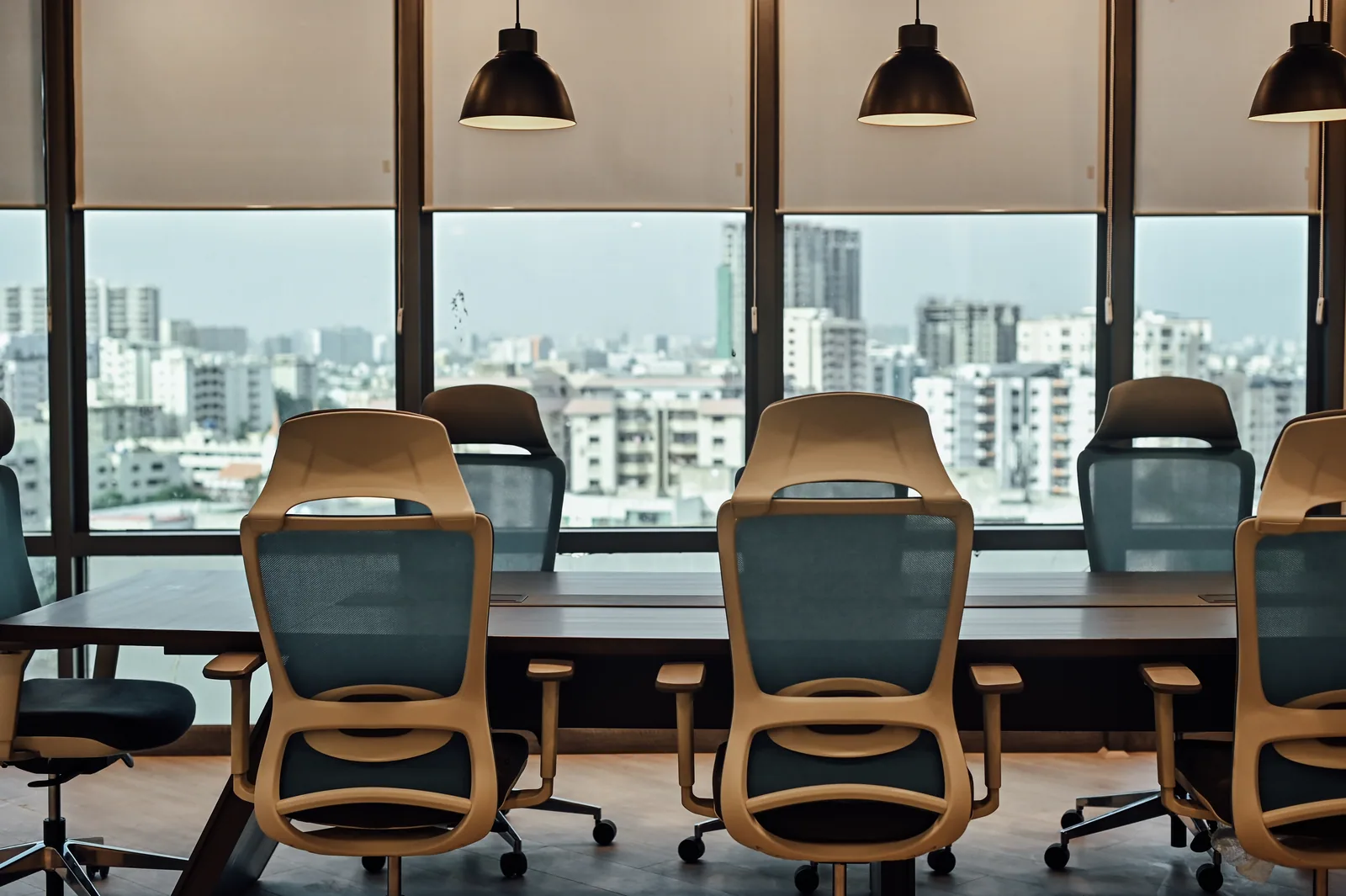 PSO House, 8th-floor rehabilitation, Karachi: Pendant lights repeat above a city-facing conference table. 8th-floor rehabilitation photography.