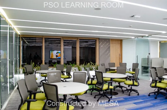 Table groups with lime-green and gray chairs beside dark-framed windows and a planted ledge, retaining original project and MESA overlays.