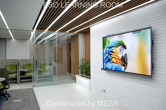 Angled view of a screen displaying a colourful bird on a white brick-textured wall beside timber-toned doors, planting and clear glass, with original overlays.