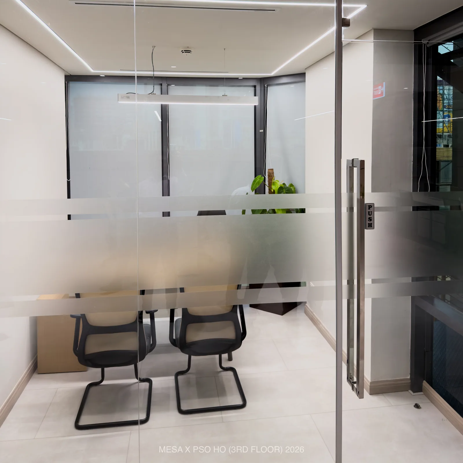 PSO House / Third floor / Frosted bands on a glass door screen a compact meeting room.