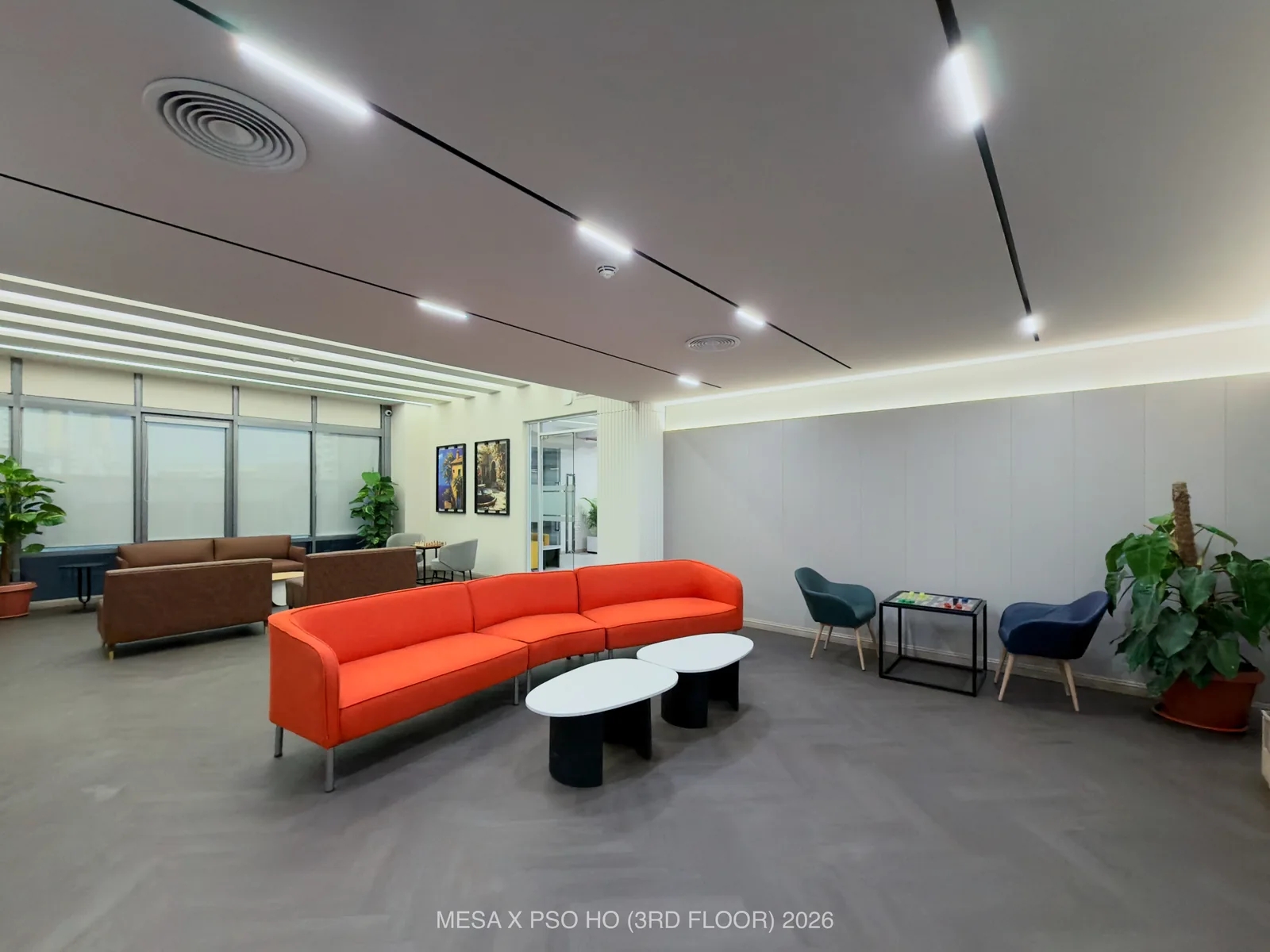 PSO House / Third floor / A curved orange sofa, visitor chairs and low tables in the reception lounge.