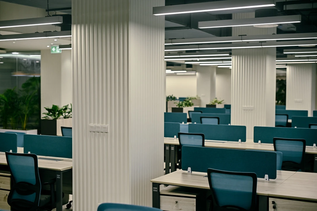 PSO 6th & 7th: Ribbed columns rise between blue workstation screens. 6th–7th-floor interior photography.