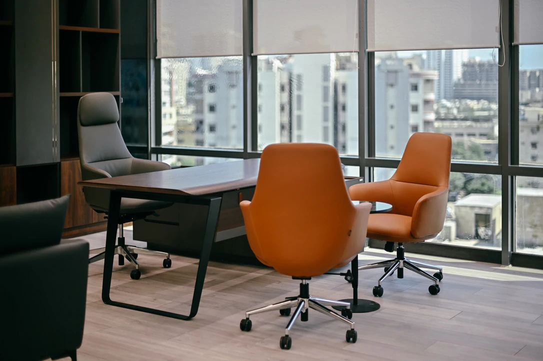 PSO 6th & 7th: A desk and orange visitor chairs beside city glazing. 6th–7th-floor interior photography.