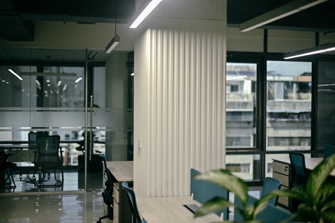 PSO 6th & 7th: A ribbed column among desks, glass and planting. 6th–7th-floor interior photography.