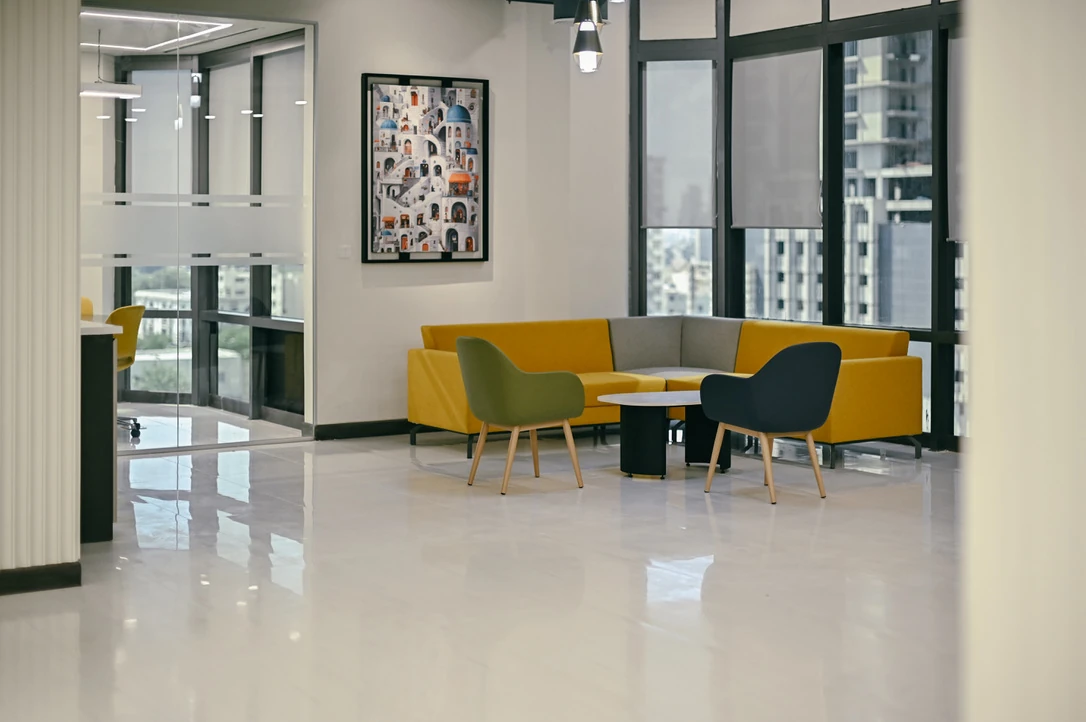 PSO 6th & 7th: A yellow corner sofa between glazed work rooms. 6th–7th-floor interior photography.