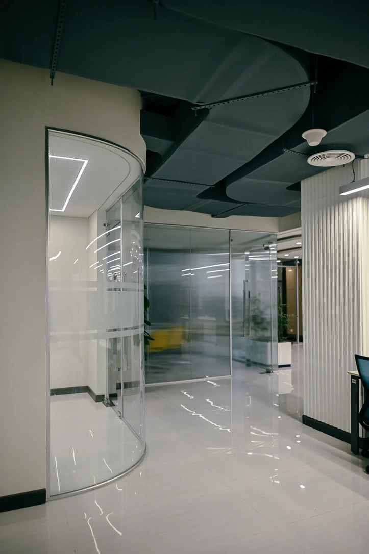 PSO 6th & 7th: A curved glazed boundary beside the office route. 6th–7th-floor interior photography.