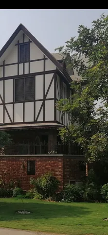 Portrait archive image of a pale gable with dark facade lines, trees, brick boundary and lawn, retaining the supplied black band at the top.