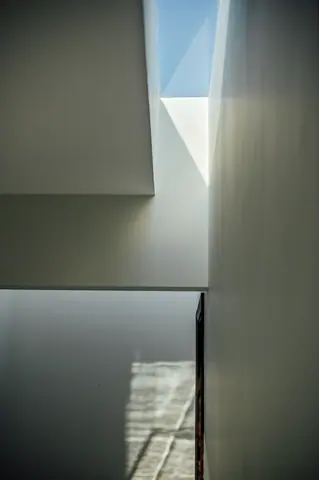 Ghalib Residence: A narrow skylight introduces daylight into the stairwell. Project photography.