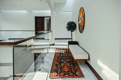 Long patterned runner and pale bench beside glass railings on an upper gallery.