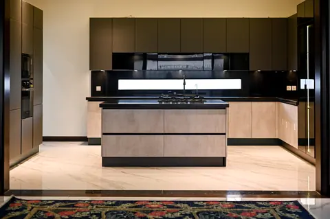 Kitchen with timber lower cabinets and island, dark upper cupboards and a long horizontal pendant.
