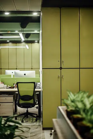 PSO House, 8th-floor rehabilitation, Karachi: Tall green cabinets frame a shared workstation. 8th-floor rehabilitation photography.