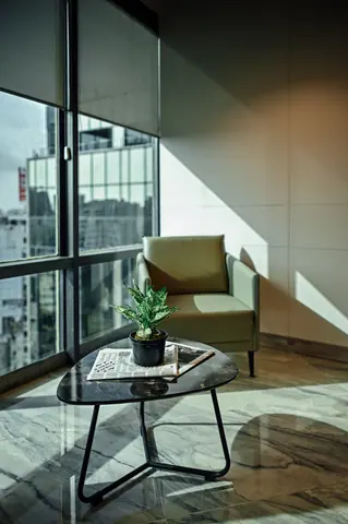 PSO House, 8th-floor rehabilitation, Karachi: A sunlit chair beside a small planted table. 8th-floor rehabilitation photography.