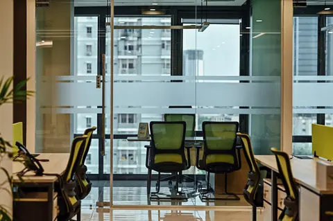 PSO House, 8th-floor rehabilitation, Karachi: Meeting chairs remain visible through a glass boundary. 8th-floor rehabilitation photography.