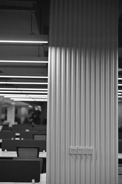 PSO 6th & 7th: A ribbed column and linear lights in monochrome. 6th–7th-floor interior photography.