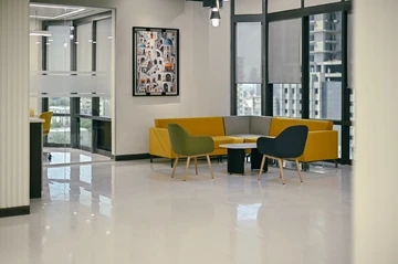 PSO 6th & 7th: A yellow corner sofa between glazed work rooms. 6th–7th-floor interior photography.